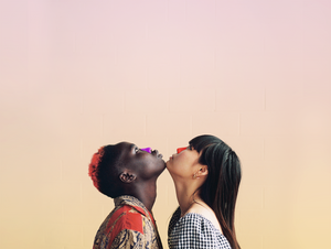 Two friends wearing colored sunscreen on their noses stand chin to chin while looking up at the sky.